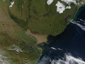 The Rio Parana in Argentina (running north-south through image center) appears brown from its sediment; it eventually drains into the Delta del Parana and the Rio de la Plata estuary. Where the Rio de la Plata empties into the Atlantic, the brown, sediment-filled river water mixes with clearer ocean water and creates swirls and cloudy formations. Visible in this image (in gray) is Buenos Aires, the capital city of Argentina, located where the Rio Parana meets the Rio de la Plata. Montevideo, Uruguay's capital, is located on the opposite side of the Rio de la Plata. Photo courtesy of NASA.