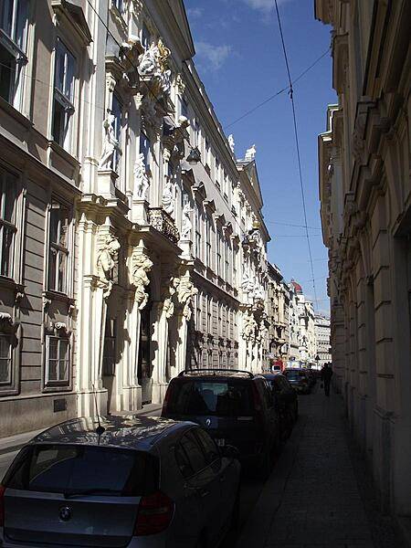 Atlantes and caryatids (male and female supporting sculptures) grace the building facade on a narrow street in Vienna.