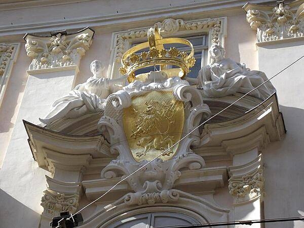 A gilded shield and crown highlight a coat of arms display over a doorway in Vienna.