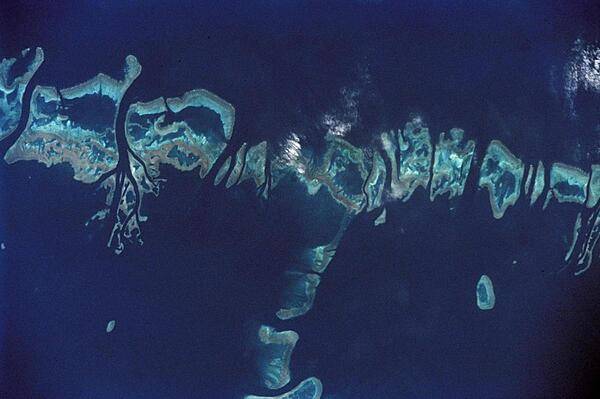 Space shuttle photo shows the Pompey Island Group in the Southern Great Barrier Reef off Australia. Ocean flow between the islands produces unique wash features in the structures of the island banks. Image courtesy of NASA.