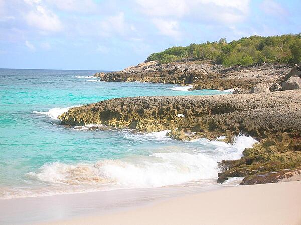 Anguilla, one of the Leeward Islands in the Caribbean, is composed of scrub-covered coral and limestone, which can be seen in this photograph of Limestone Bay. The island's many bays and pristine beaches draw visitors from around the world, making tourism Anguilla's main industry.