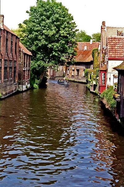 Sightseeing boat on a Brugge canal. The name of Brugge, often called the Venice of the North, is believed to come from the Old Norse word Bryggia meaning 'mooring place.' The canals were important in getting trading goods to their destination. Today, they are used exclusively for tourist boats.
