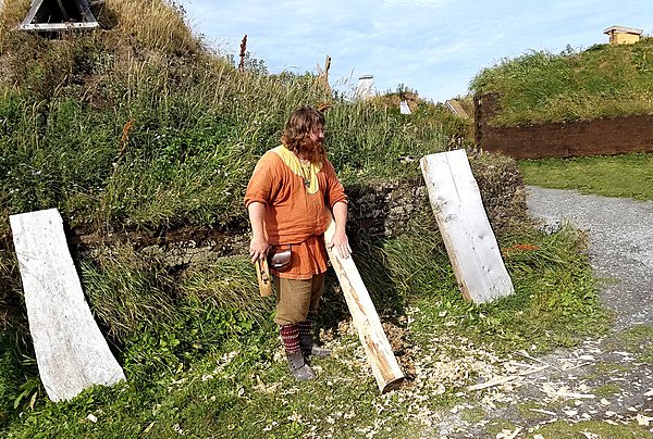 A Norse-period interpreter at L’Anse Aux Meadows planing logs.