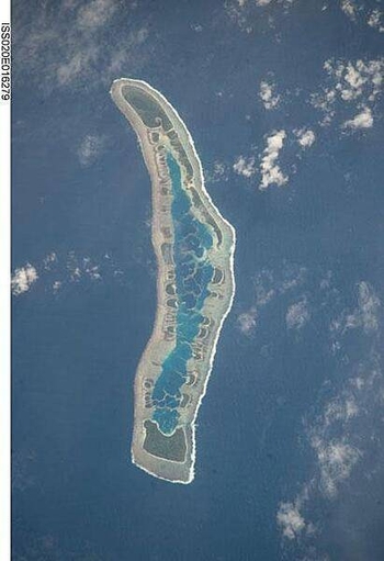 Millennium Island - known as Caroline Island prior to 2000 - is located at the southern end of the Line Islands, which make up the western portion of Kiribati. Uninhabited Millennium Island is formed from a number of smaller islets built on coral reefs. The reefs grew around a now-submerged volcanic peak, leaving a ring of coral around an inner lagoon. The shallow lagoon waters are a lighter blue than the deeper surrounding ocean water; tan linear "fingers" within the lagoon are the tops of corals. The two largest islets are Nake Islet (on the north) and South Islet. Image courtesy of NASA.