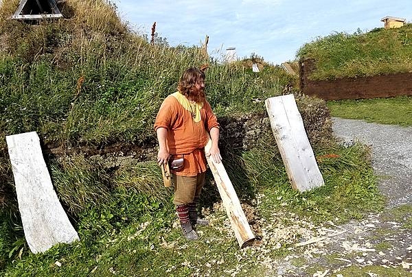 A Norse-period interpreter at L’Anse Aux Meadows planing logs.