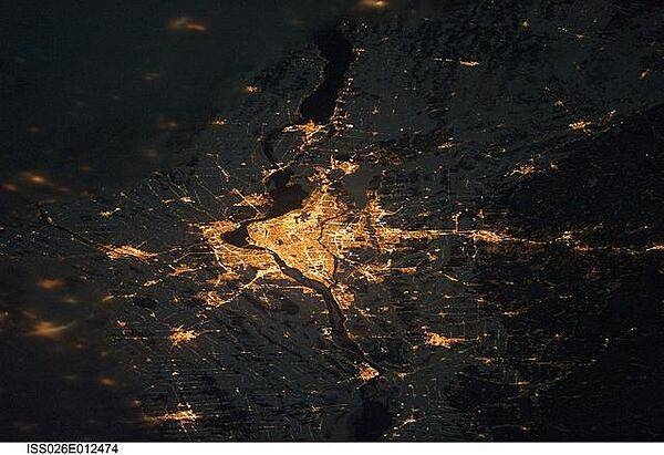 A night view of the Montreal metropolitan area is featured in this image from the International Space Station. This photo of the Montreal, Quebec metropolitan area (center) illustrates the extent of urbanization made clearly visible by city lights at night. Major roadways and industrial areas are traced by bright white lighting, while the adjacent residential and commercial land uses are characterized by more diffuse yellow-gold lighting. Rivers and other water bodies appear black, while the surrounding rural countryside is faintly illuminated by moonlight. Blurry areas at top and bottom left are caused by cloud cover. Montreal is the largest city in the dominantly French-speaking province of Quebec, and the second-largest in Canada, after Toronto. While the city of Montreal proper is located on - and almost completely covers - the Island of Montreal at the confluence of the St. Lawrence (center) and Ottawa Rivers (not visible), the city takes its name from Mont Royal located at the city's center. Image courtesy of NASA.