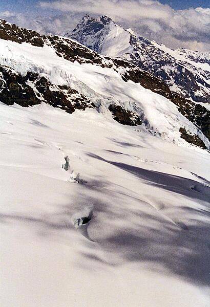 Snow, rocks, shadows, and peaks merge upward into the clouds.