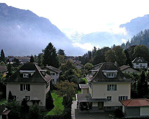 Sturdily built Swiss homes lie in the shadows of some imposing mountains.