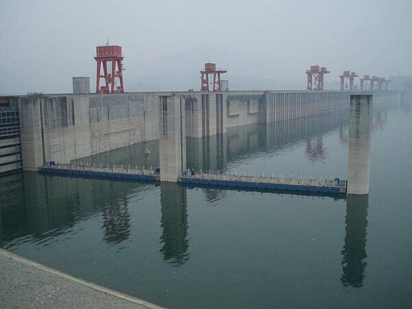 The Three Gorges Dam at Sandouping is the largest hydroelectric power station in the world. It provides power and controls water flow to prevent floods and to supply water downstream during times of drought. Its construction forced the relocation of 1.3 million people and the flooding of thousands of cities, towns, and historical sites. This is a view of the reservoir behind the dam.