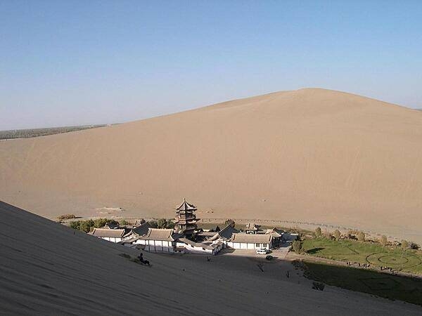 Crescent Moon Lake is an oasis in the Singing Sands Mountains, six kilometers south of Dunhuang. The lake gets its name from its shape. Activities in this area include camel riding, dune paragliding, and sand sledding. Most tourists visit in the evening to avoid the heat.