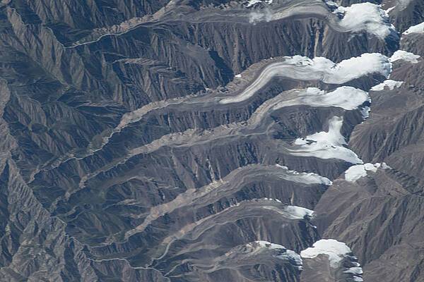 Glaciers in the Qilian Mountain range of central China as viewed from the International Space Station at an altitude of about 400 km (250 mi). The icy tongues extend to the left from the higher elevations at the right.   Image courtesy of NASA.