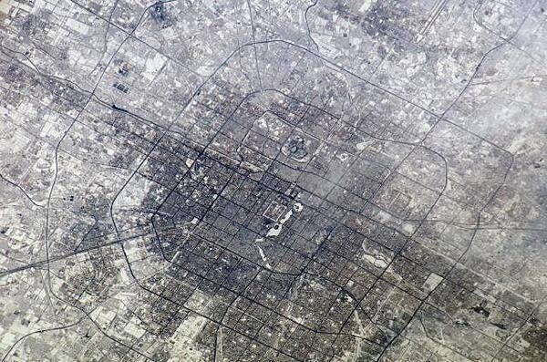 The concentric street patterns of Beijing are clearly visible in this photo taken from the International Space Station. The rectangular area in the center is the Palace Museum also known as the Forbidden City. The area of buildings north of the Forbidden City contains a number of universities. Beijing is surrounded by six ring roads or beltways, four of which may be seen in this photo. The 1st Ring Road no longer functions as an expressway. Image courtesy of NASA.