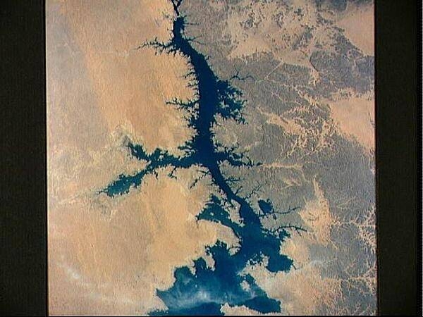 The Aswan High Dam (top of photo) is 4 km (2.5 mi) across and 111 m (364 ft) high. Completed in 1971, it was constructed to supply cheap hydroelectric power to both Egypt and Sudan by impounding, controlling, and regulating the flood waters of the Nile River in Lake Nasser, the world's second largest artificial lake. The lake extends over 800 km (500 mi) in length, covers an area of some 5,200 sq km (2,000 sq mi) and is as much as 107 m (350 ft) deep at the face of the dam. Click on photo for higher resolution. Image courtesy of NASA.