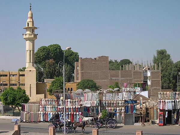 A streetside clothes market in Luxor with a minaret in the background.