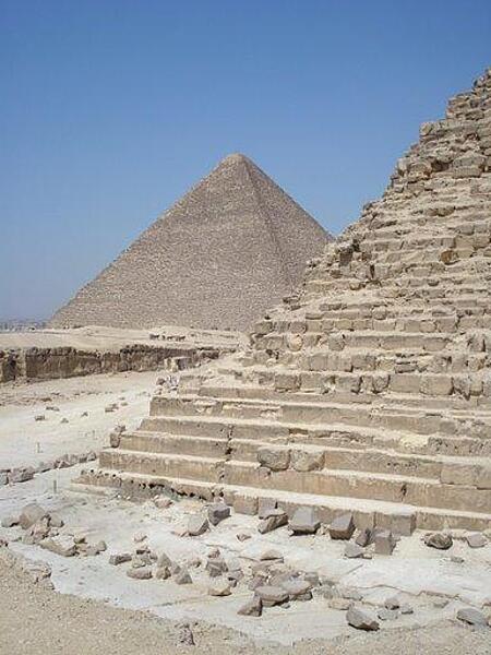 A view of a corner of the Khafre     pyramid reveals its stair-step construction. The Great Pyramid of Khufu appears in the distance.
