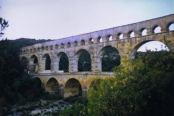 The Roman aqueduct at Pont du Gard, built during the mid-first century A.D., was part of a 50 km (30 mi) long aqueduct system that brought water to the city of Nemausus (today's Nimes). Built entirely without the use of mortar, its construction is thought to have taken about three years using 800 to 1,000 workers.