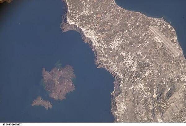This view illustrates the center of Santorini Volcano, located approximately 120 km (75 mi) north of Crete in the Aegean Sea. One of the largest volcanic eruptions in the past 10,000 years occurred approximately 1630 B.C. on this island. The cataclysm created the present-day islands and caldera bay of Santorini Volcano. The caldera rim is clearly visible in this image as a steep cliff forming the western shoreline of the island of Thera, the largest of the remnant islands. The white rooftops of cities and towns also help trace the caldera rim. Image courtesy of NASA.