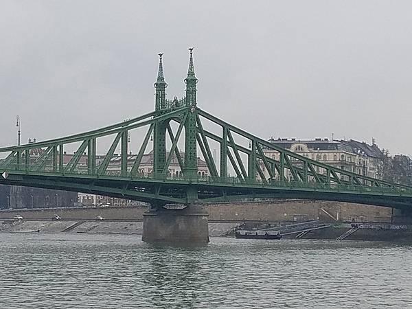 The Liberty Bridge (or Freedom Bridge) in Budapest is one of several bridges across the River Danube that connects the Buda and Pest halves. Built between 1894 and 1896 as part of Budapest's Millennium World Exhibition, the Art Nouveau bridge incorporates mythological turul bird sculptures into its spires and the country's coat of arms into its side.