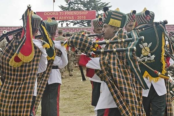 The Pipes and Drums of the Madras Regiment perform during the Yudh Abhyas 2016 closing ceremony on 27 September 2016, at Chaubattia Military Station, India. The Madras Regiment is one of the oldest regiments in the Indian Army whose establishment dates to 1758. The insignia of the Madras Regiment, visible in this photograph, consists of a pair of crossed swords behind a circular shield surmounted by an Assaye Elephant above a scroll reading “Madras Regiment.” The Assaye Elephant crest is in recognition of the regiment’s valor in the Battle of Assaye (1803). In addition, the distinctive black pom-pom worn by the regiment is visible on the turbans of the band members. Yudh Abhyas, Hindi for “training for war,” is a bilateral training exercise geared toward enhancing cooperation and coordination between the US and Indian armies through training and cultural exchanges. Photo courtesy of the US Army/ Staff Sgt. Samuel Northrup.