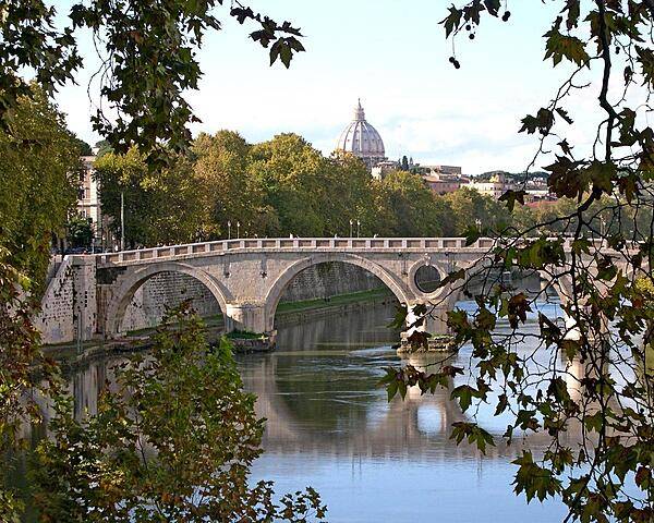 The Garibaldi Bridge over the Tiber River in Rome. The dome of St. Peter's Basilica appears in the background.