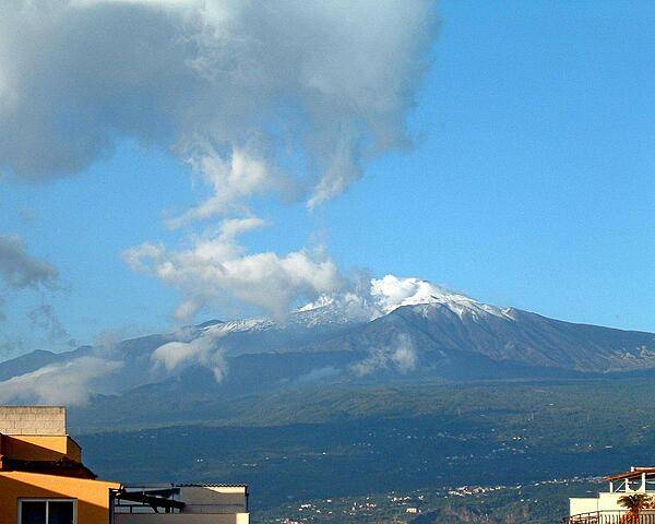 Mt. Etna, the largest active volcano in Europe, looms over rooftops on the island of Sicily.