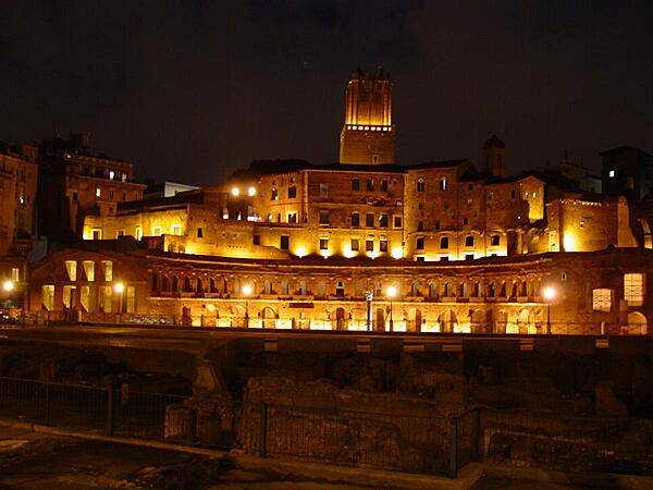 A nighttime view of Trajan's Market in Rome. Now a complex of ruins, it was built in A.D. 100-110. Its upper floor was filled by offices; a road divided it  from the lower floor, which held shops.