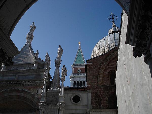 A view of the Cathedral of St. Mark's in Venice showing some of the saints adorning its roof, and a peek at its bell tower.