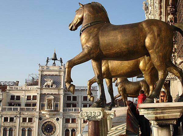 View of St. Mark's Square in Venice showing the famous Greek horses and the astronomical clock. The bronze horses were originally installed at the Hippodrome in Constantinople and so date back to at least the 4th century. In 1254 they came to Venice where they remained until 1797 when they were brought to Paris by Napoleon. In 1815 they were returned to Venice. The originals are now in St. Mark's Museum. The original astronomical clock was built between 1496-99. It has been renovated many times, most recently in 1996.