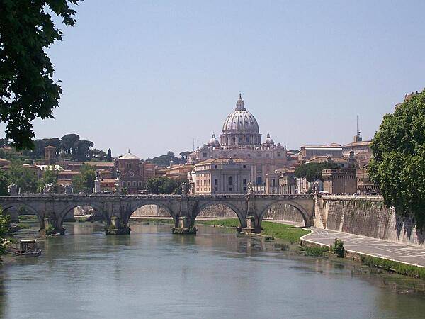 The Vittorio Emanuele Bridge over the Tiber River in Rome with Vatican City in the background. The bridge was completed in 1911.