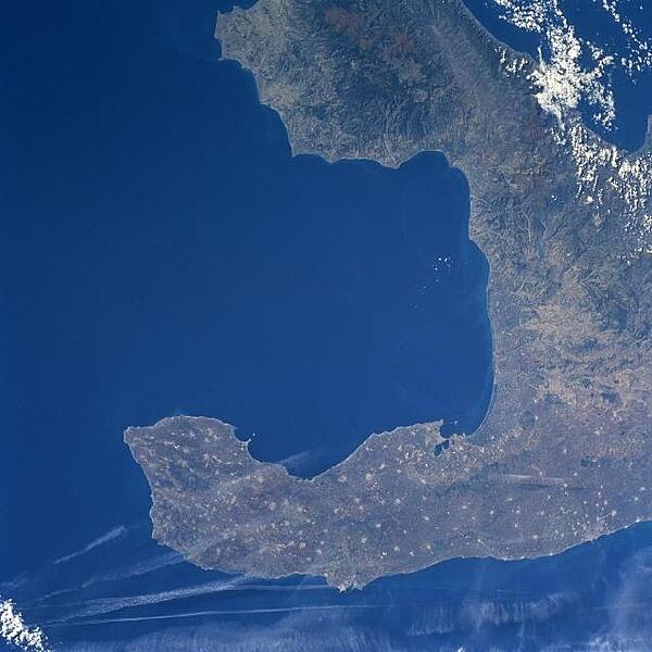 The Salentino Peninsula (bottom of image), also known as "the heel of Italy," is the elongated promontory that juts southeasterly from the larger Italian Peninsula. This peninsula is bordered by the Adriatic Sea to the northeast (bottom of image) and the Gulf of Taranto to the southwest (center of image). The peninsula consists of gently rolling hills and coastal plains, thereby promoting an agrarian economy. The numerous, light-colored spots seen throughout the peninsula show the location of small agricultural towns and villages. Photo courtesy of NASA.