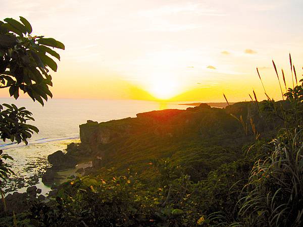 Sunrise over a verdant Okinawan shoreline.
