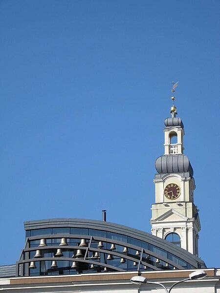 The bells in the forground were originally cast in the 13th century, but were remounted on the roof of the Riga City Council (Town Hall) building in the late 20th century. The modern carillon forms a striking contrast to the Town Hall's 18th century clock tower. The bells chime every hour on the hour.