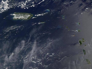 A view of Puerto Rico (upper left) and the isles of the Lesser Antilles. The Soufriere Hills Volcano on the island of Montserrat began emitting steam and ash on 9 February 2006. Low-level activity continued for several days. The volcano produced another plume on 20 March 2006, which is captured on this image. The volcano's pale beige ash plume blows westward over the Caribbean Sea. The red outline shows where the satellite detected a thermal anomaly, an area where the ground surface was significantly hotter than its surroundings. Image courtesy of NASA.
