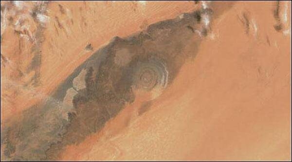 The Richat Structure, a prominent circular feature in the Sahara Desert of Mauritania, has attracted attention since the earliest space missions because it forms a conspicuous bull's-eye in the otherwise rather featureless expanse of the Gres de Chinguetti Plateau in central Mauritania. The Structure, which has a diameter of almost 50 km (30 mi), has become a landmark for space shuttle crews. Initially interpreted as a meteorite impact structure, it is now thought to be merely a symmetrical uplift (circular anticline) laid bare by erosion. Image courtesy of NASA.