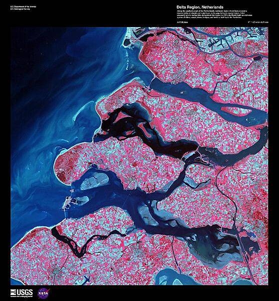 Along the southern coast of the Netherlands, sediment-laden rivers have created a massive delta of islands and waterways in the gaps between coastal dunes. The area in this false-color satellite image is extensively farmed, giving the photo its patchwork look. The Dutch have built an elaborate system of dikes, canals, dams, bridges, and locks to hold back the North Sea because of rising sea levels and devastating historic floods. The Dutch coastline has changed significantly over time due to these floods, such as the 1134 storm that formed the Zeeland archipelago when water covered massive swaths of land. Other major floods include St. Lucia's Day flood in 1287, St. Elizabeth's Day flood in 1421, and a massive flood in 1953 that sparked the building of the Delta works system in place today. The Delta works will be under stress in coming years as sea levels continue to rise. Image courtesy of USGS.