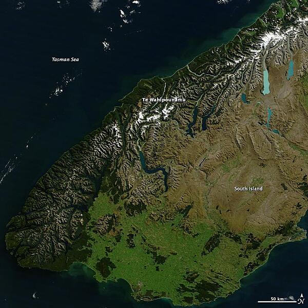 Te Wahipounamu, "the greenstone waters," is a sacred place in the Maori culture of New Zealand. The foreboding mountains and steep-walled valleys on New Zealand's southwest coast are the places of Atua, "the gods." Additionally, the streams that wash down from the glacier-capped peaks carry a highly prized stone, a hard, translucent, green rock that the Maori carved into jewelry and blades, for both tools and weapons. Most New Zealand greenstone is nephrite - a form of jade - though some is bowenite, another mineral. From space, the west coast of New Zealand resembles the greenstone for which it is named. Dark green native forest extends from the mountain tree line to the shore. The forest harbors unique and endangered animals like the kiwi and takahe, both flightless birds, and the kea, the only alpine parrot. The lighter green land in the southeast was once forested, but is now grassland or agriculture. Te Wahipounamu is wilderness, and New Zealand has set the land aside to conserve it. The entire 2.6 million ha (6.4 million acres) that make up the southwest coast of the South Island (about 10 percent of New Zealand's land area) is divided between four national parks, state forests, and other conservation areas. The natural and cultural significance of Te Wahipounamu led UNESCO to declare it a World Heritage area in 1990. Image courtesy of NASA.