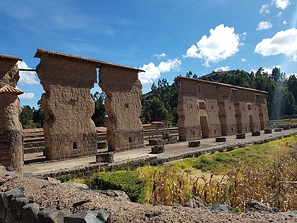 Central wall of the huge two-story Inca Temple of Viracocha at Raqchi; the remains are some 100 m long and 14 m high. The original building consisted of a central adobe wall some 18 to 20 meters in height with a cut stone foundation base. Windows and doors allowed passage from one side to the other. The central wall was flanked on either side by a row of eleven columns. The foundations for both the wall and the columns were constructed of classic high Inca stonework with the remaining height built of adobe. (The 4 m height of the wall foundation survives, but most of the column heights have been reduced.) Prior to its destruction by the Spaniards, the temple had what was likely the largest single gable roof in the Incan Empire, with its peak at the central wall and stretching out over the columns on each side. The  site is at 3,480 m above sea level and 110 km from Cusco.