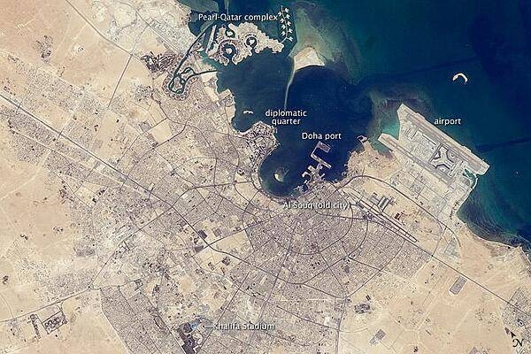 The old and new zones of Doha, the capital city of Qatar, are clearly visible from the International Space Station. The old city comprises the ancient bazaar, or Souq, near the dhow harbor, which is still used today for traditional Arab sailing vessels. Modern port facilities have sprung up to the east of the Souq.
Subsequent developments have sprouted progressively further from the ancient center, with ring roads concentrically arranged around it. The diplomatic quarter is reached via the waterfront Corniche promenade, north of the old city. Further away, an extensive marina known as West Bay Lagoon, with boating access to the Persian Gulf, stands out (image top).
Qatar's new artificial island, known as the Pearl-Qatar, is under construction with 32 km of new coastline just offshore of West Bay Lagoon. This development is intended mainly as a residential zone, with themes based on Arabic, Mediterranean, and European cultures. The Pearl-Qatar is so named because it is being built on one of Qatar's historical pearl diving sites. A string of small islands built along the outer margin is intended to recall the pearl-diving culture of the nation's past. Image courtesy of NASA.