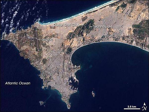 In the 1940s, Dakar occupied just the southern tip of the Cap Vert Peninsula. Today, the cityscape has sprawled both northward and eastward. In the southern part of this satellite view, piers from the peninsula protrude into the ocean, looking like rows of jagged teeth. Throughout the southern portion of the peninsula, gray hues, straight lines, and sharp angles reveal paved roads and buildings spreading toward the north. In the northwest, a long, straight line outlined by green indicates the runway of Dakar's airport. East of the airport, a large area of green reveals Technopole, a protected area and popular bird-watching destination. Photo courtesy of NASA.