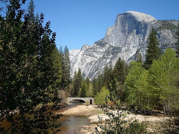 Rising nearly 1,500 m (5,000 ft) above Yosemite Valley, Half Dome is a Yosemite National Park icon and a great challenge to many hikers. This view is looking eastward and shows Stoneman Bridge in the middle distance. Image courtesy of the US National Park Service.