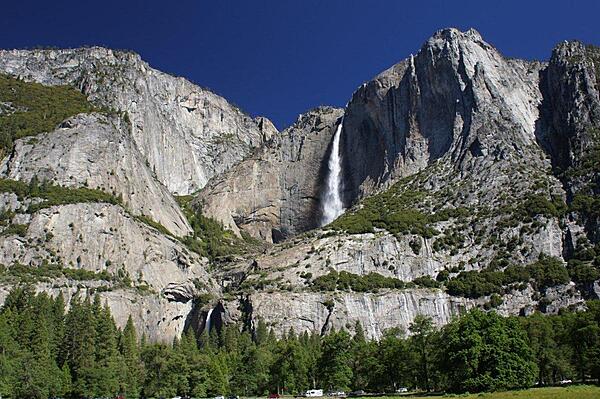 This iconic view of Yosemite Falls, a major attraction in Yosemite National Park in California, shows both the upper and lower falls. The falls come from Yosemite Creek, rushing in the spring from snow melt. The upper fall plunges some 436 m (1,430 ft) from the valley rim, making it alone among the 20 highest falls in the world. The combined drop of 739 m (2,425 ft) for the upper fall, middle cascades, and lower fall make Yosemite Falls the highest measured falls in the United States.