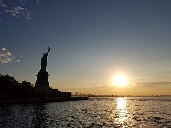 Statue of Liberty in silhouette with the sun rising in the distance. Photo courtesy of the National Park Service.