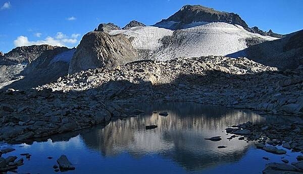 Ice age glaciers played an essential role in shaping Yosemite’s landscape. Most of this ice had melted away due to natural warming by about 10,000 years ago. During a more recent cold period called the Little Ice Age, small glaciers formed below the highest peaks. Currently, two remain: the Maclure glacier and the Lyell glacier (shown). These ice bodies are important to local ecosystems because they provide a year-round supply of cold water to the Lyell Fork of the Tuolumne River, especially during the late summer and fall after the winter snowpack has melted. Image courtesy of the US National Park Service.