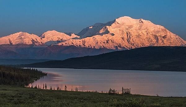 Denali, North America’s tallest mountain at 6,190 m (20,308 ft), is tinged orange-pink by alpenglow (an optical phenomenon that appears as a reddish glow near the horizon opposite the sun when the solar disk is just below the horizon). Photo courtesy of the US National Park Service/ Kent Miller.